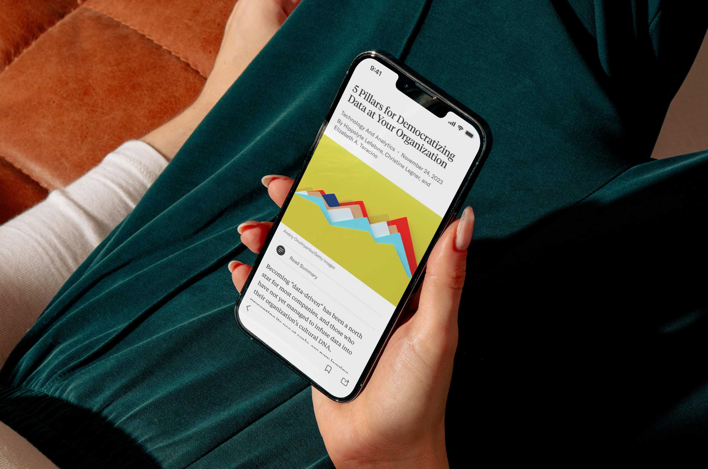 Person holding a phone in their lap looking at the Harvard Business Review mobile app.